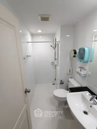Modern bathroom with sleek fixtures and white tiles, featuring a shower and sink.