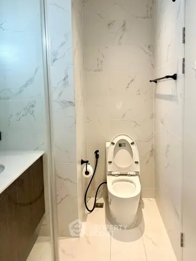 Modern bathroom with sleek fixtures and marble tiles, featuring a contemporary toilet and vanity.