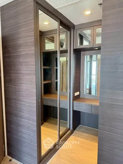 Luxurious walk-in closet with mirrored sliding doors and elegant wood finish.