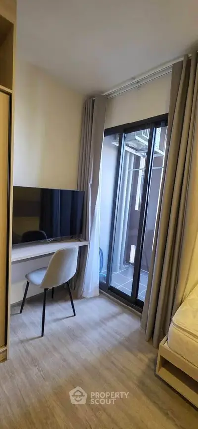 Modern bedroom with sleek TV setup and balcony access in stylish apartment.