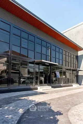 Modern commercial building with sleek glass facade and spacious entrance.