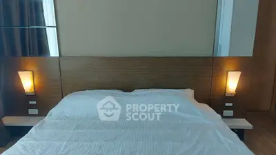 Cozy bedroom with modern lighting and wooden accents, perfect for relaxation.