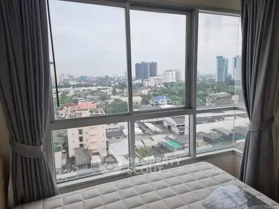 Spacious bedroom with panoramic city view through large windows, perfect for urban living.