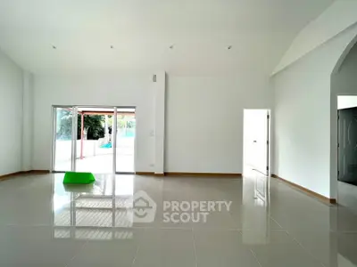Spacious modern living room with glossy tiled floors and large sliding glass doors leading to a patio.