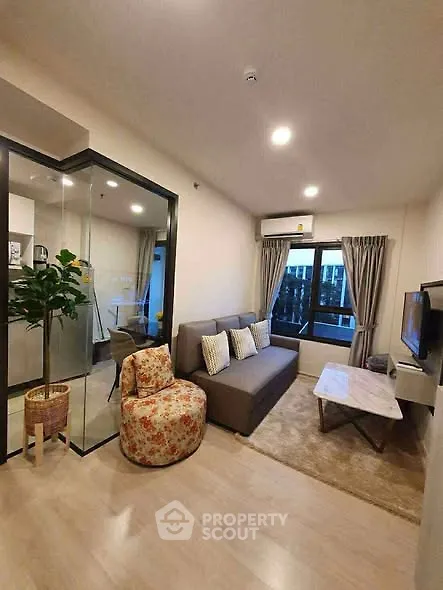 Modern living room with cozy seating and large windows in a stylish apartment.