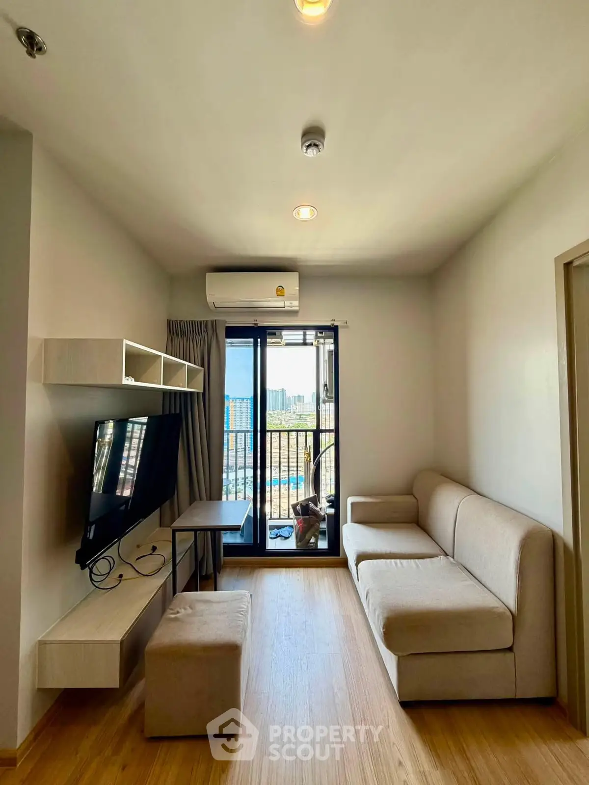 Modern living room with cozy sofa, wall-mounted TV, and balcony view in a stylish apartment.