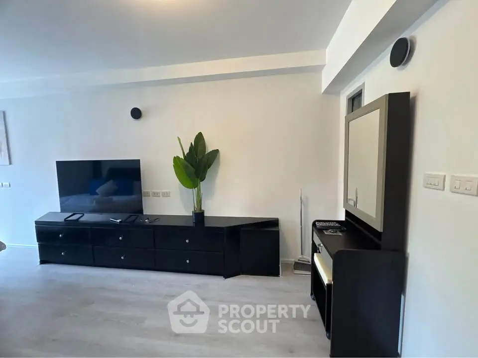 Modern living room with sleek black furniture and large TV