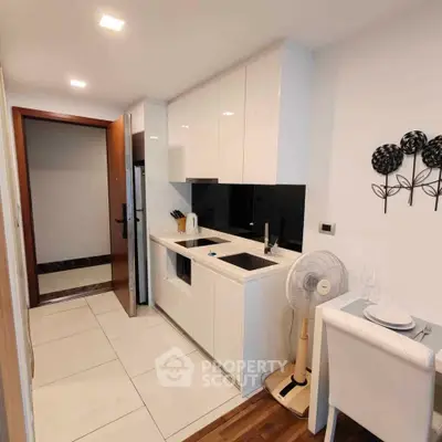 Modern compact kitchen with sleek white cabinets and integrated appliances in a stylish apartment.