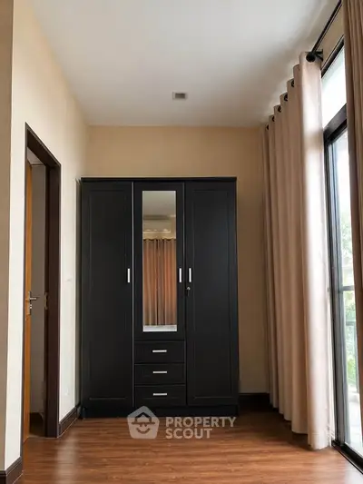 Spacious bedroom with elegant wardrobe and large window for natural light.