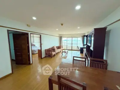Spacious living room with wooden flooring and elegant furniture, featuring a view of the balcony.