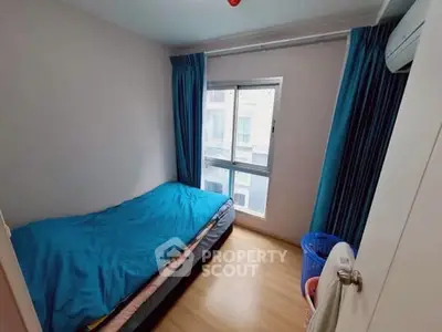 Cozy small bedroom with blue bedding and natural light from window