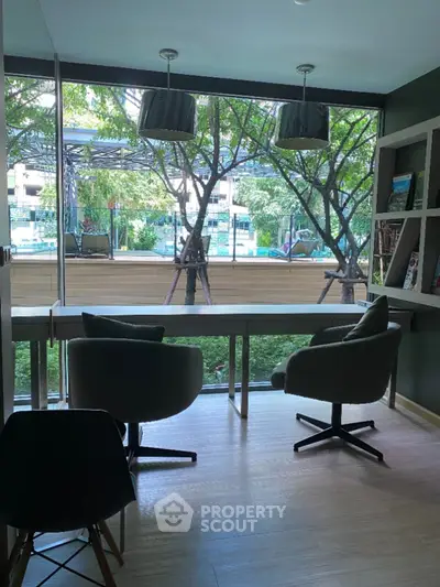 Modern study room with large window and stylish chairs overlooking greenery.