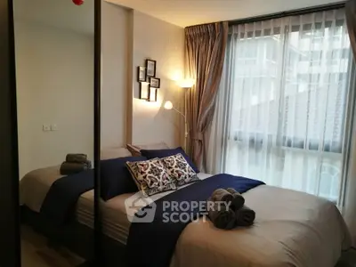 Cozy bedroom with modern decor and large window offering natural light.