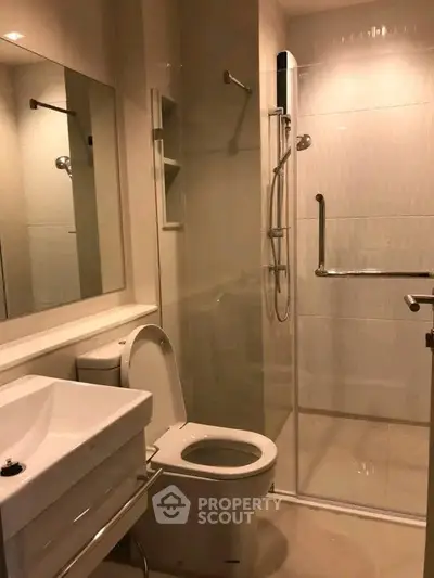 Modern bathroom with glass shower and sleek fixtures in contemporary apartment.