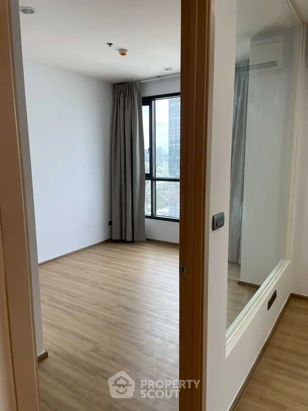 Spacious empty room with wooden flooring and large window view