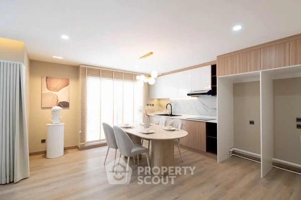 Modern kitchen with open layout and elegant dining area, featuring sleek cabinetry and stylish decor.