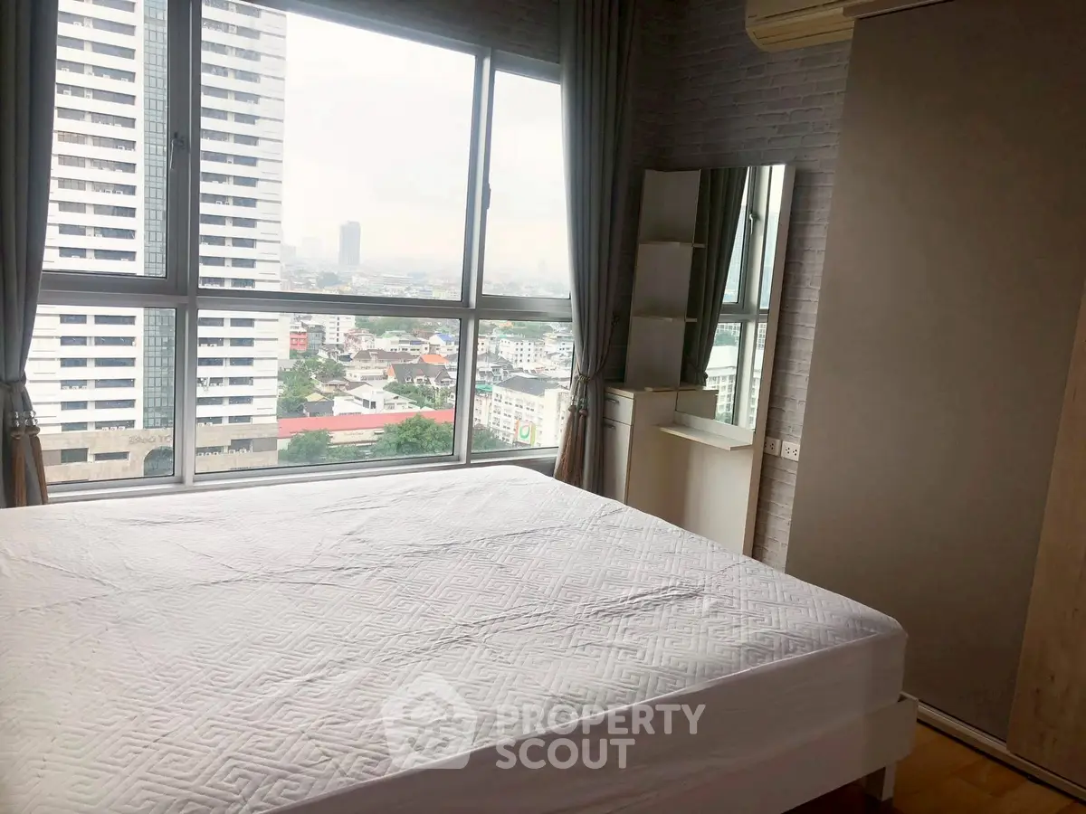 Spacious bedroom with large windows offering stunning city views.