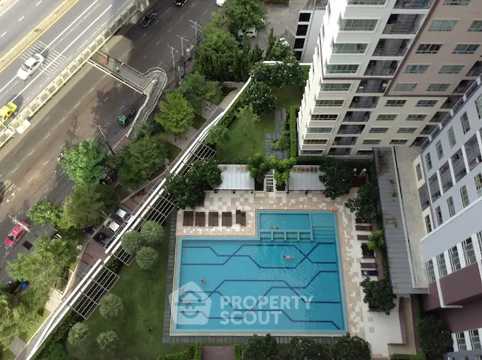 Stunning aerial view of modern residential building with luxurious swimming pool and lush greenery.