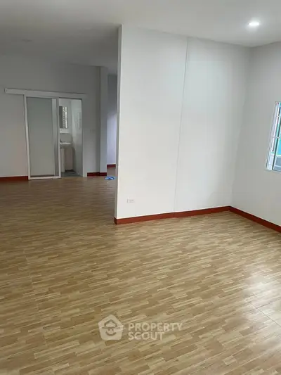 Spacious open-plan living area with wooden flooring and ample natural light.