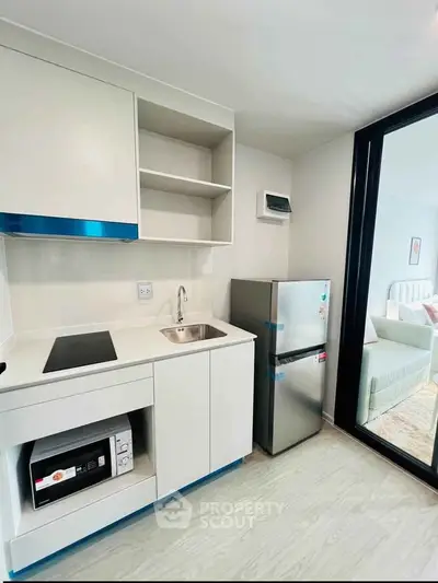 Modern compact kitchen with sleek appliances and open shelving in a bright apartment.