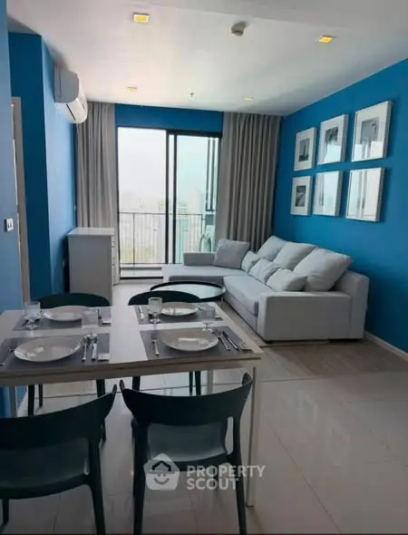 Modern living room with blue walls, stylish furniture, and balcony access in a contemporary apartment.