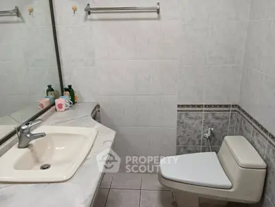 Spacious bathroom with modern sink and toilet, featuring elegant tile design.