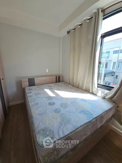 Cozy bedroom with large window and natural light, featuring a comfortable bed and modern decor.