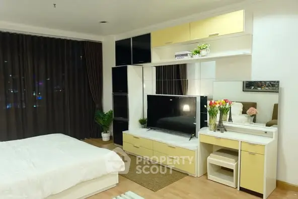 Modern bedroom with stylish furniture and large TV, featuring elegant decor and cozy ambiance.