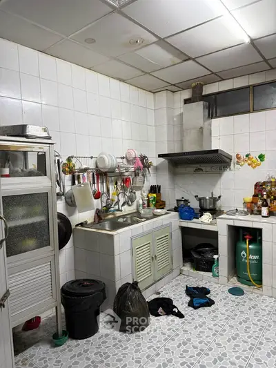 Cozy kitchen with tiled walls and floor, featuring a gas stove and ample storage space.