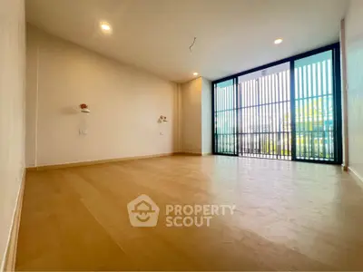 Spacious empty room with large windows and wooden flooring, perfect for customization.