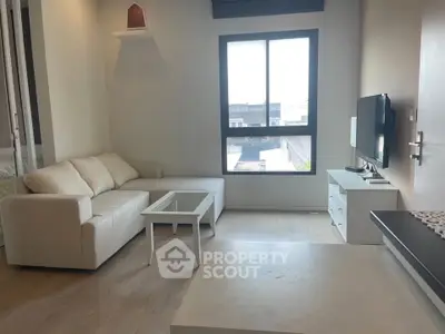 Modern living room with sleek furniture and large window offering natural light.