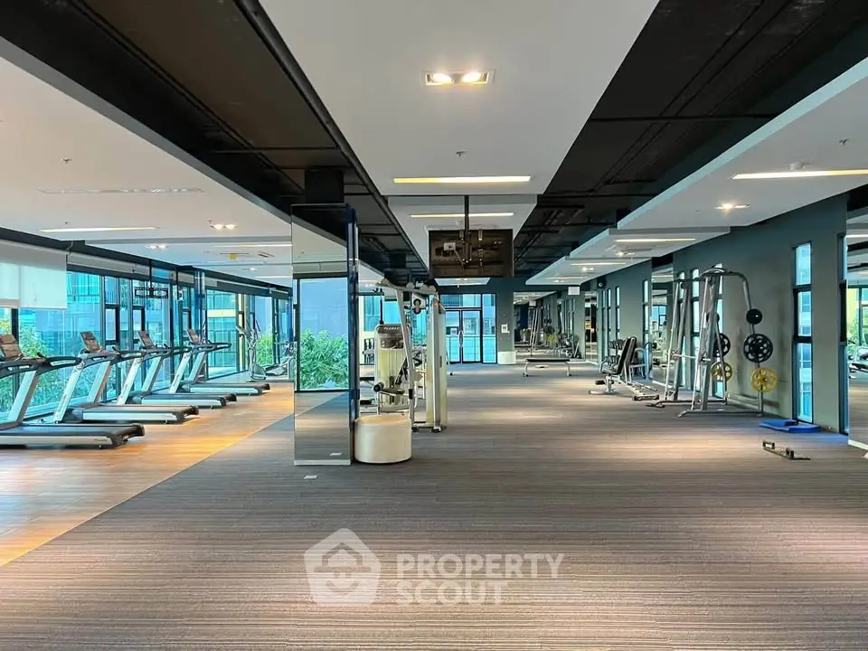 Spacious modern gym with state-of-the-art equipment and large windows offering natural light.