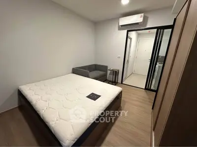 Modern bedroom with minimalist design featuring a cozy bed and sleek air conditioning unit.