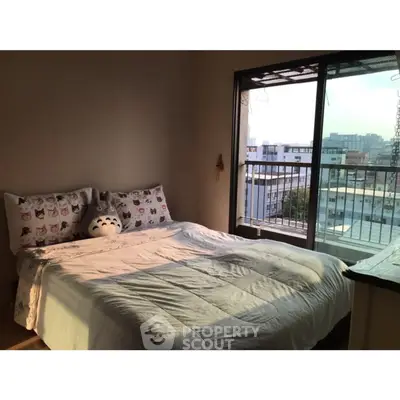 Cozy bedroom with large window and city view, featuring plush bedding and balcony access.