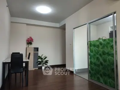 Spacious living room with modern decor and wooden flooring, featuring a dining area and glass partition.