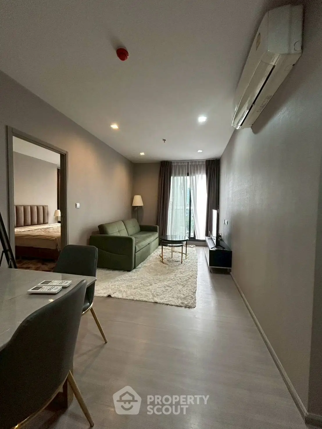 Modern living room with sleek furniture and natural light, adjacent to a cozy bedroom.