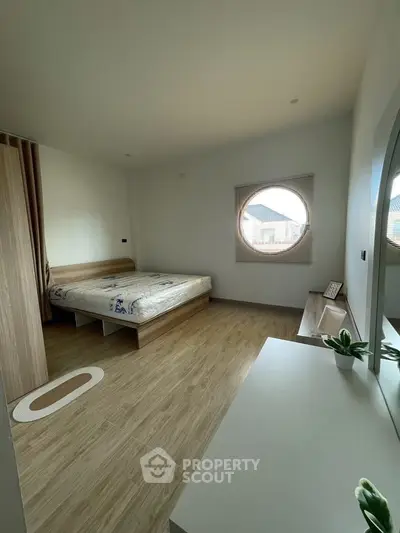 Spacious bedroom with unique round window and modern decor