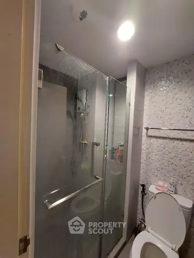 Modern bathroom with glass shower and tiled walls, featuring a sleek design.