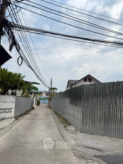 Narrow residential alley with metal fence and overhead power lines