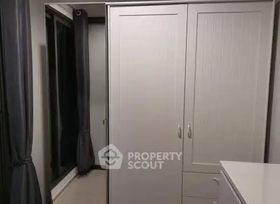 Modern bedroom with sleek wardrobe and large window for natural light.