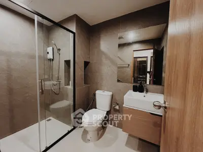 Modern bathroom with glass shower and sleek fixtures in contemporary home.