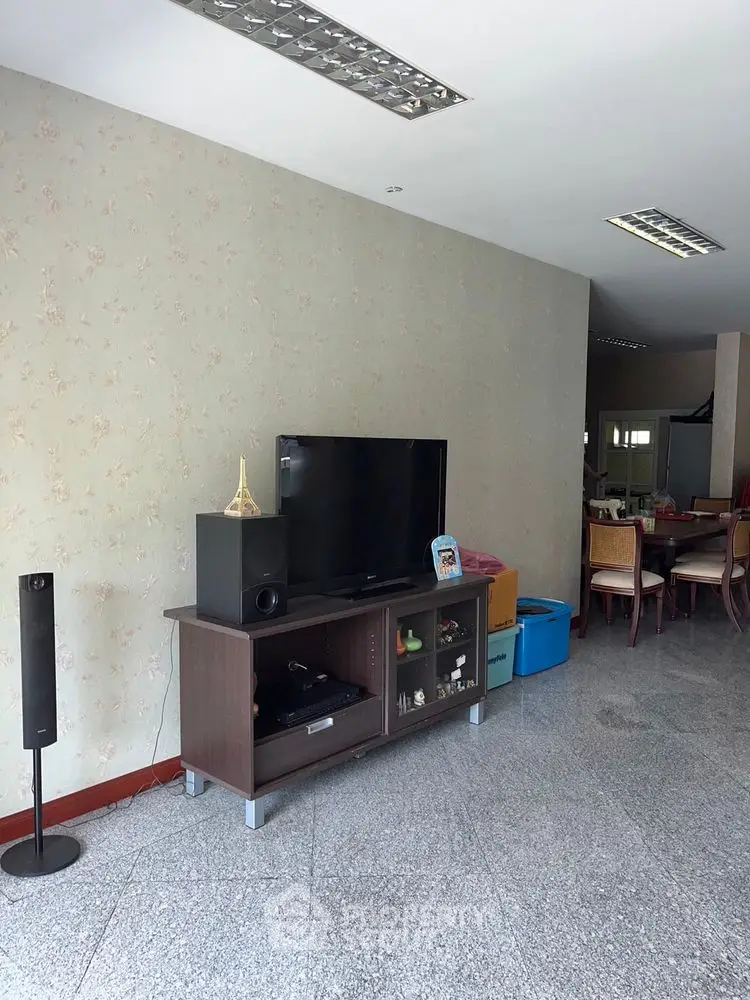 Spacious living room with modern TV setup and elegant dining area