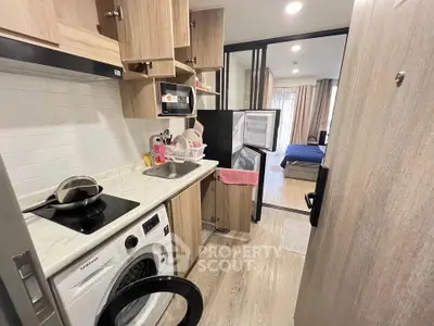 Compact kitchen with modern appliances and open layout leading to cozy bedroom.