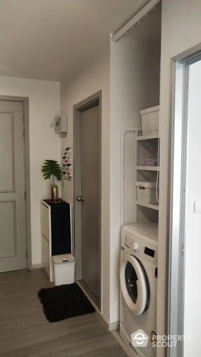 Modern laundry area with washing machine and storage shelves in a stylish apartment.