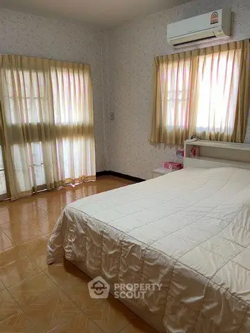 Cozy bedroom with natural light and air conditioning, featuring a comfortable bed and elegant curtains.