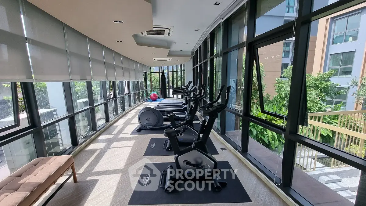 Modern gym with panoramic windows and exercise equipment in a luxury residential building.