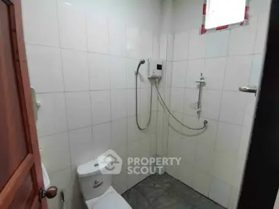 Compact bathroom with shower and toilet in a tiled setting
