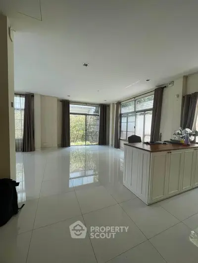 Spacious modern living room with large windows and sleek tile flooring