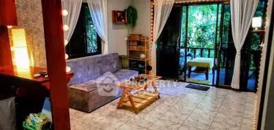 Cozy living room with large windows and garden view, featuring a comfortable sofa and stylish decor.