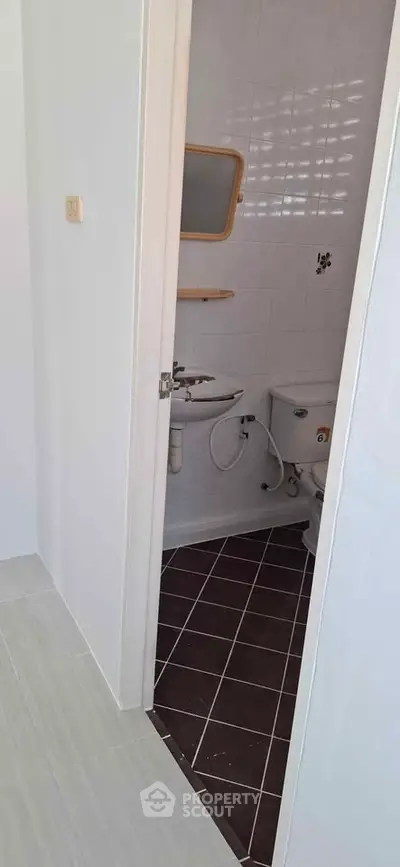 Compact bathroom with white tiles and basic fixtures, ideal for small apartments.